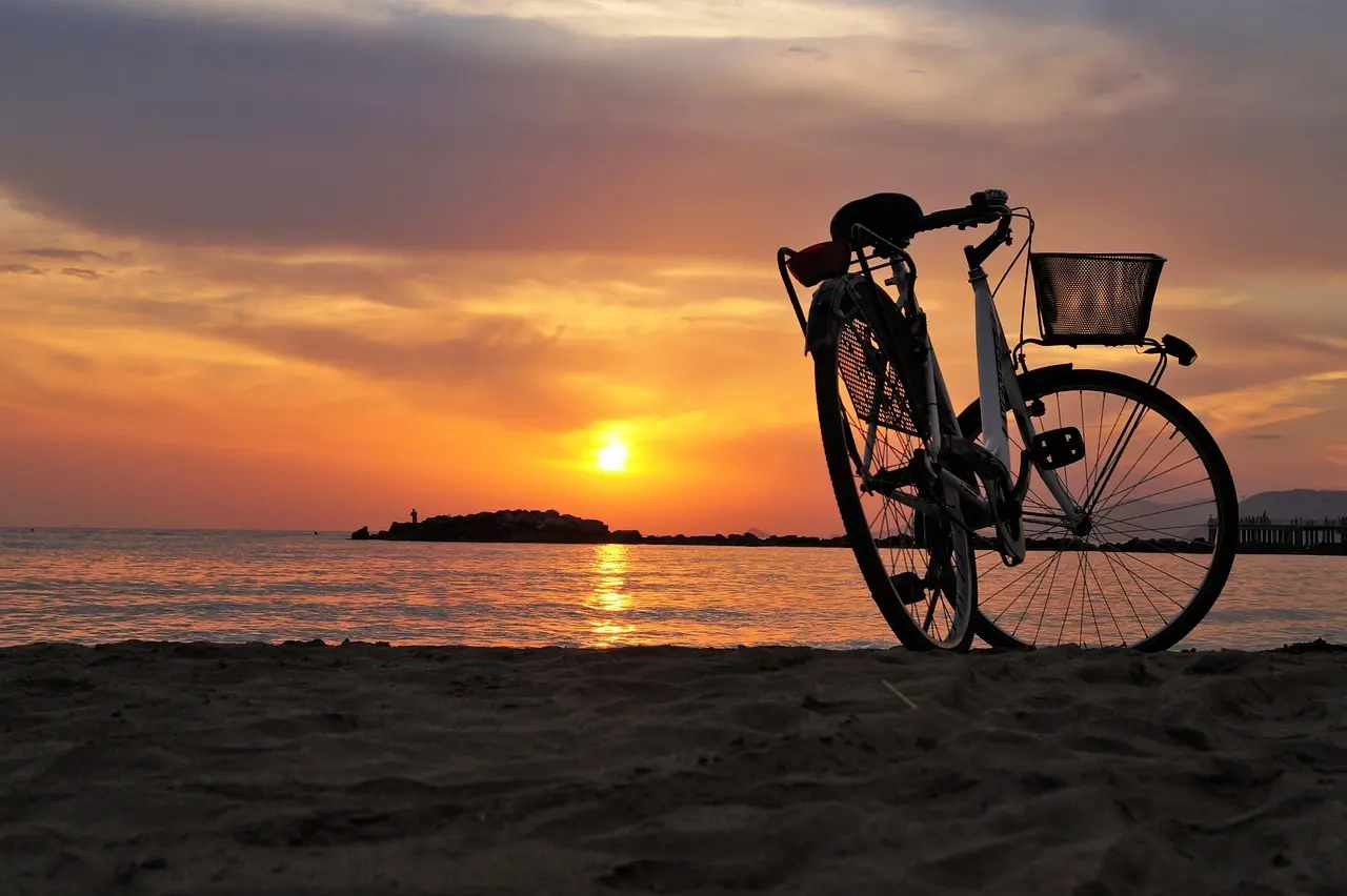 Cykel i silhuet på strand ved solnedgang